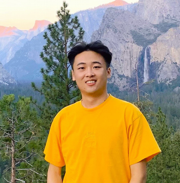 Student wearing a yellow shirt posing in nature