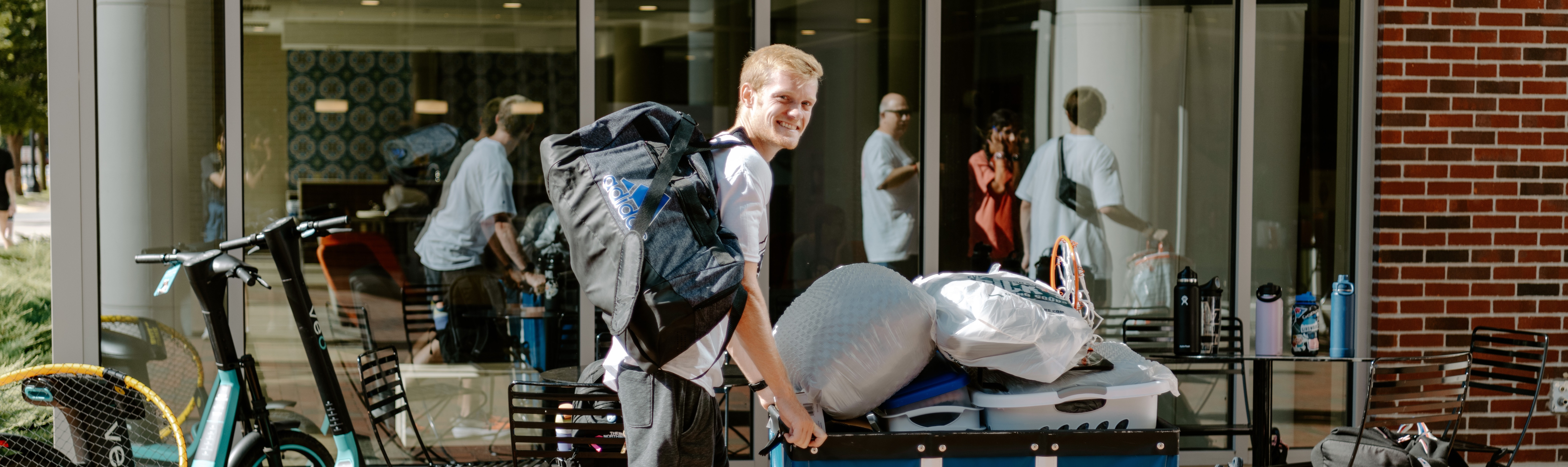 Decorative banner image showing a student moving a cart of belongings into a dorm