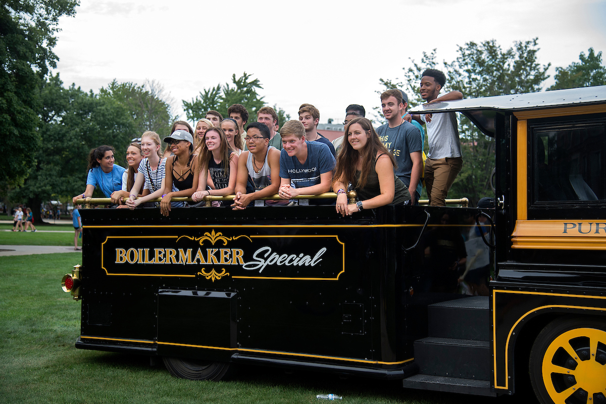 decorative image of Purdue students posing in the Boilermaker Special train car during Boiler Gold Rush