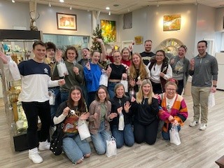 Fifteen students posing at the All Fired Up glass shop.
