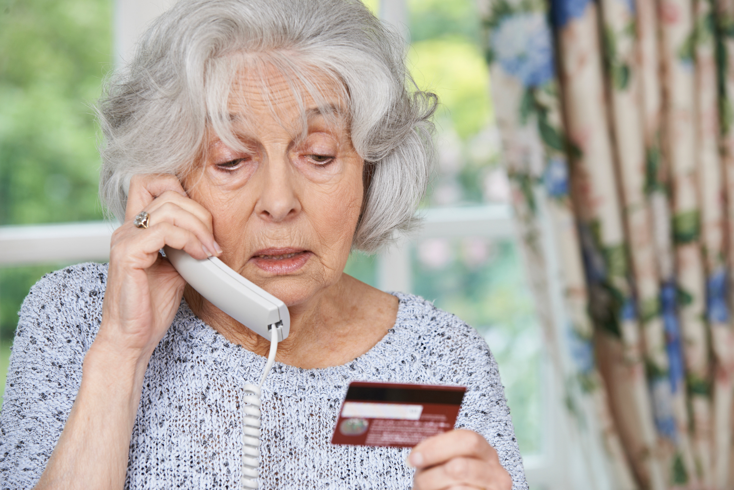 Senior woman giving credit card information over the phone.