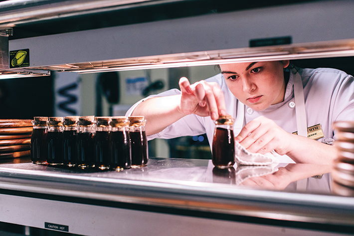 Katherine Meinzen, a senior in hospitality and tourism management, wipes drips from the wild mushroom consommé vessels.