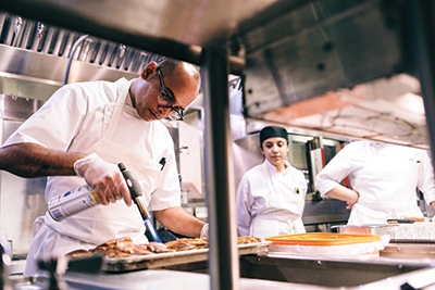 Chef Ambarish Lulay sears duck breasts as students watch.