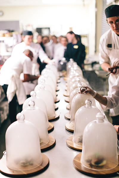 The main course, topped with smoke-filled glass domes, is lined up for service. 