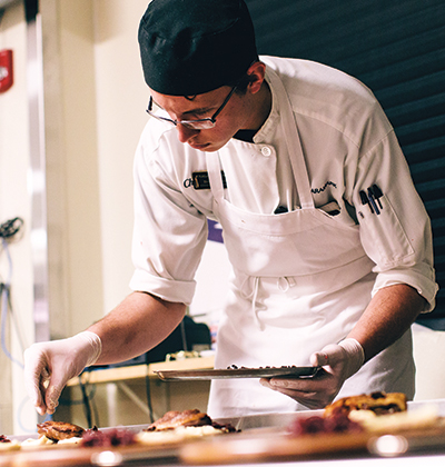 Bryan Tishmack, a sophomore in hospitality and tourism management, puts the finishing touches on the main course.