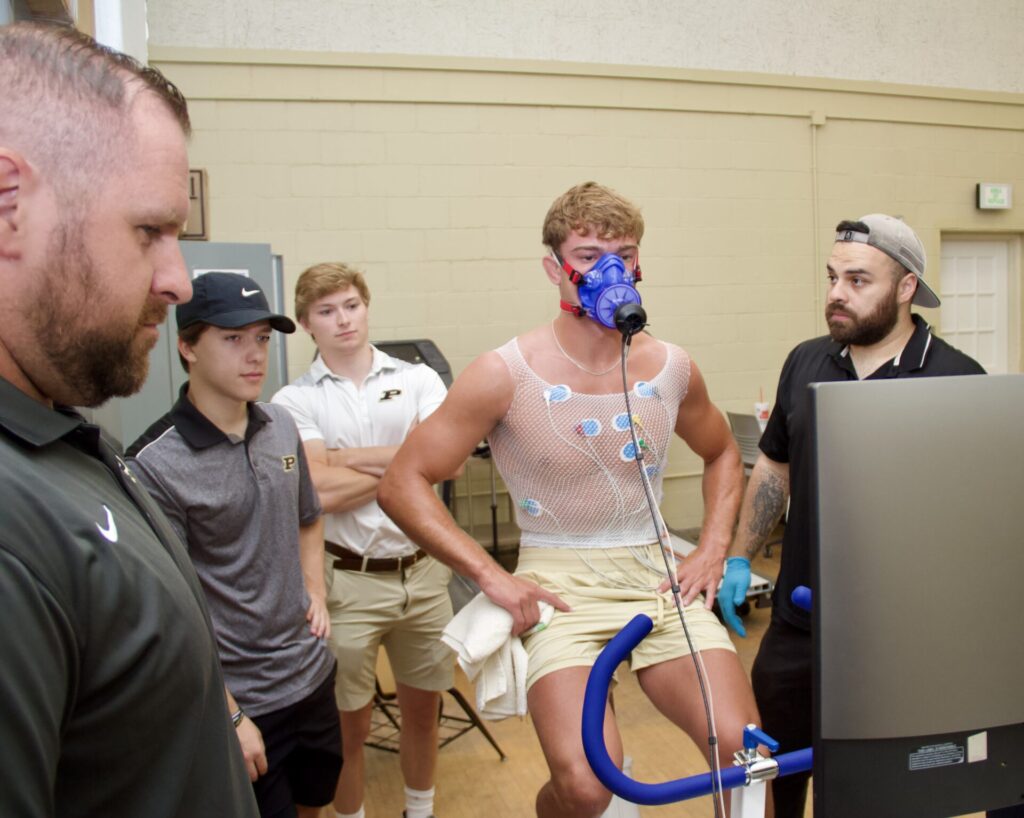 Members of the Purdue Department of Health and Kinesiology monitor a Purdue wrestler on an exercise bike.