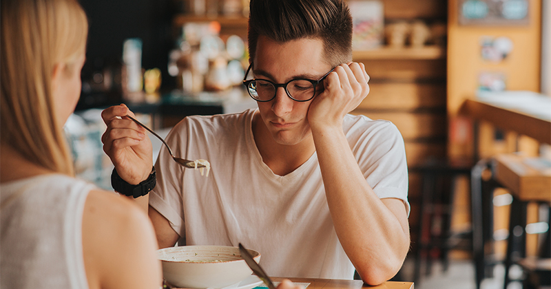 A man in glasses looks at a bowl of bland-looking food with dissatisfaction. (Adobe Stock Image)