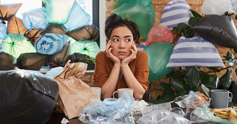 A person is surrounded by clutter and looks overwhelmed