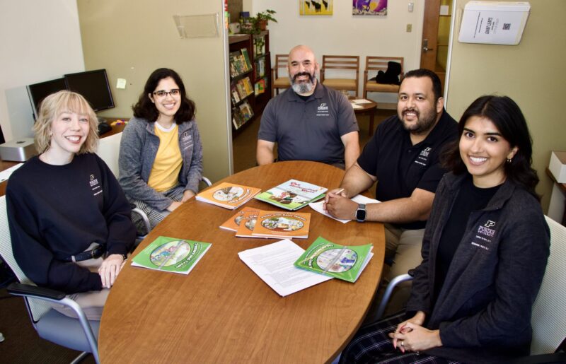 David Purpura sits at a table with his four post docs.