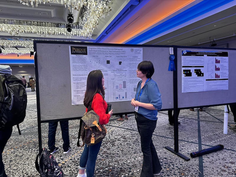 Students talk to each other in front of a research poster.