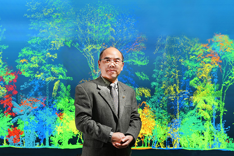 Purdue Institute for Digital Forestry director Songlin Fei in front of a screen that displays a digital forest created from the remote sensing taken by his collaborators. 