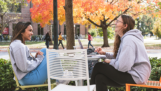 Two Purdue students sitting at a table outdoors.