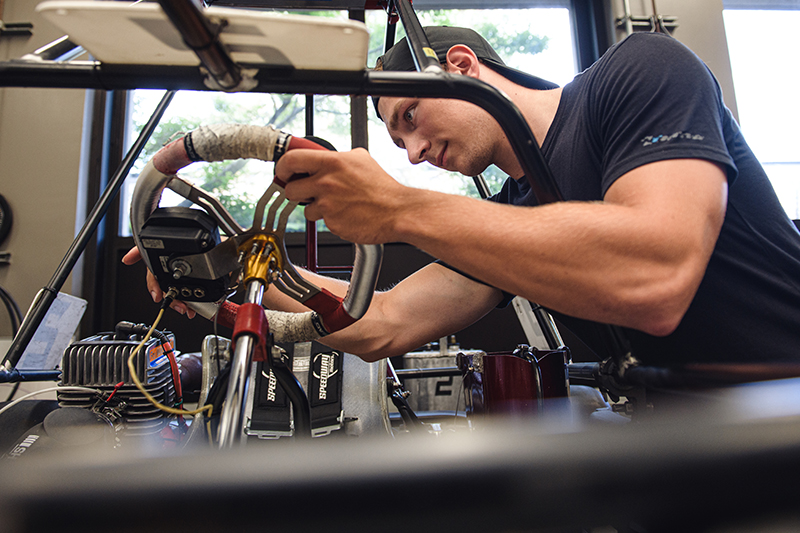 A motorsports engineering student analyzing a steering wheel.