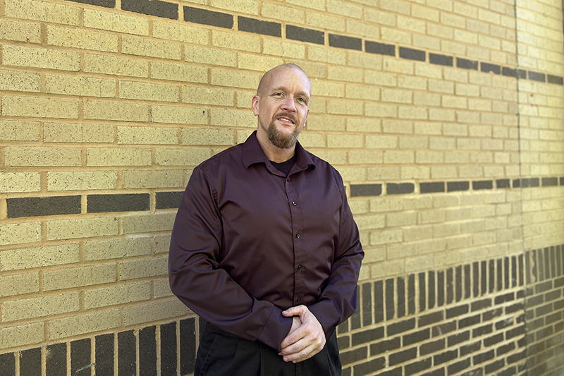 Student Josh Vandergriff poses in front of a brick wall