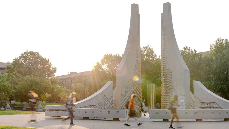 Students walking past the Engineering Fountain at sunrise