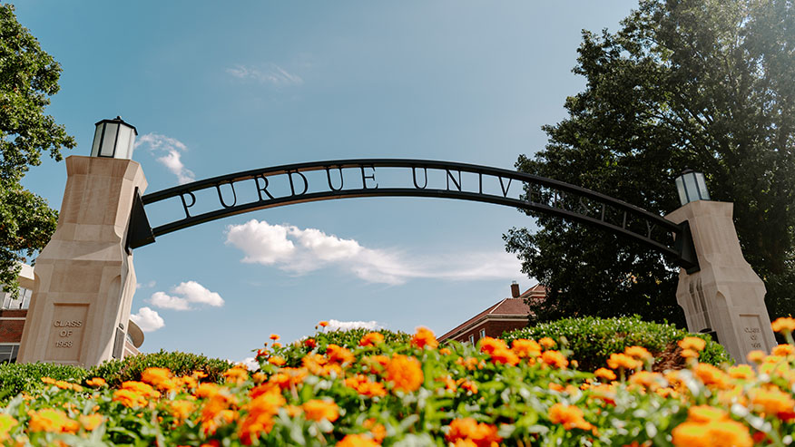 Flowers growing beneath Purdue University’s Gateway to the Future arch on a sunny summer day