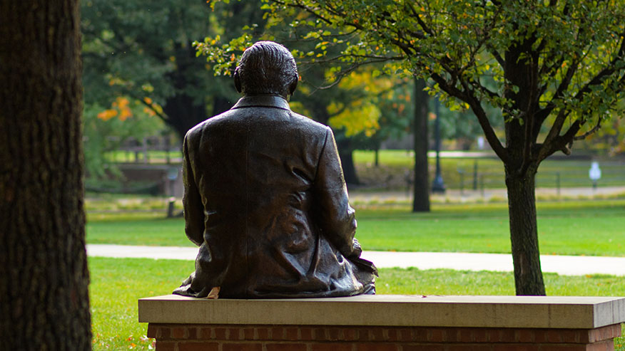 A photo of the John Purdue statue, taken from behind, as it looks over the university’s Memorial Mall.