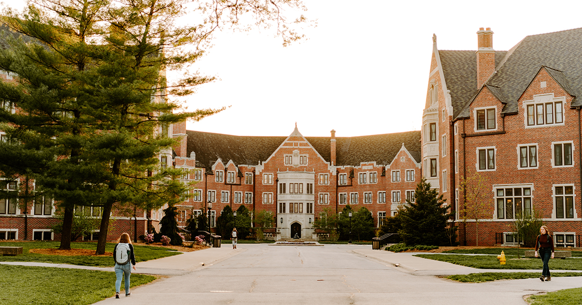 Three students walk to or from Windsor Halls on Purdue’s campus under a sunny sky