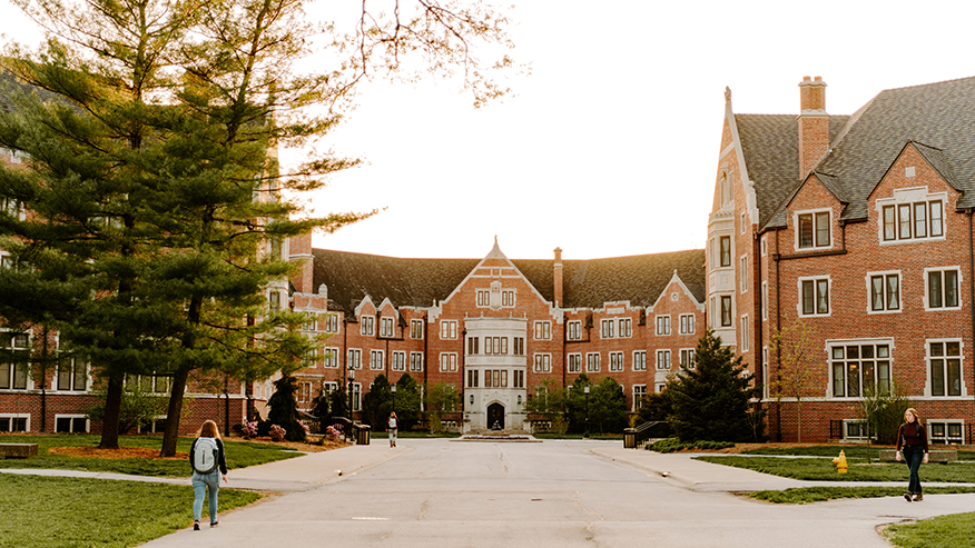 Three students walk to or from Windsor Halls on Purdue’s campus under a sunny sky