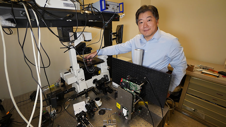 A Purdue researcher looks at the camera while operating 3D nanoprinting technology in his laboratory.