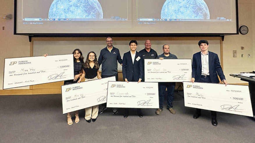 Two Purdue Innovates Incubator leaders stand with five Purdue University students, who hold five oversized checks.