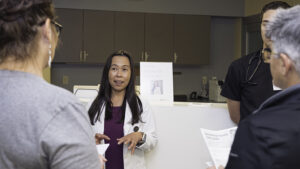 A nurse practitioner talks to two people in a medical setting.