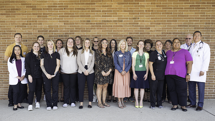 A group of employees stand together in front of a brick wall.