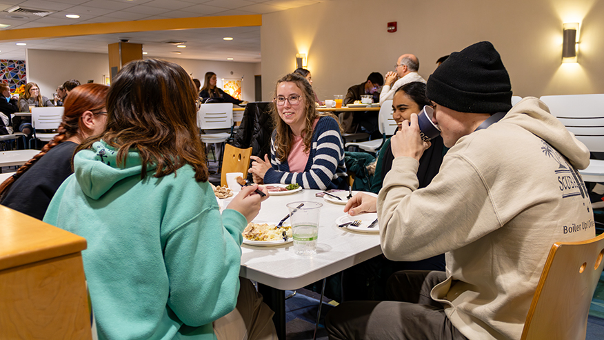 Students sit at a table eating their Thanksgiving dinner