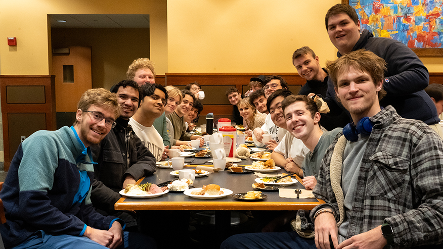 A group of students sits at a table for Thanksgiving dinner