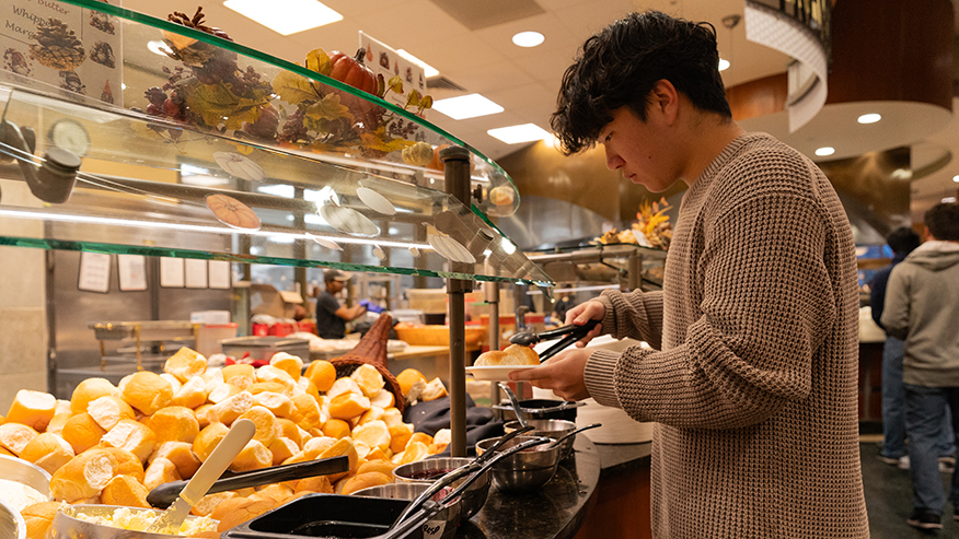 A student picks up a roll with tongs