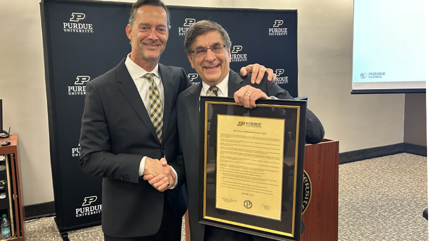 Mike Berghoff shakes hands with Frank Dooley, who is holding a framed resolution of appreciation