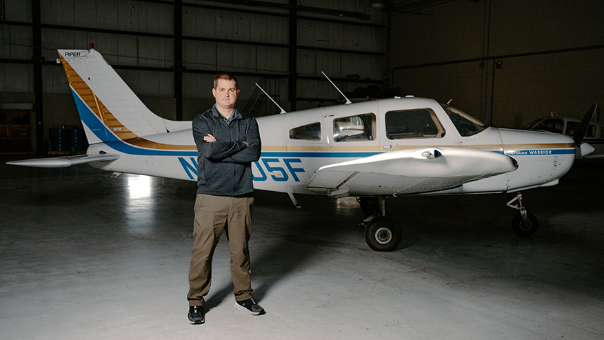 Adrian Mullins standing next to an airplane in a hangar.