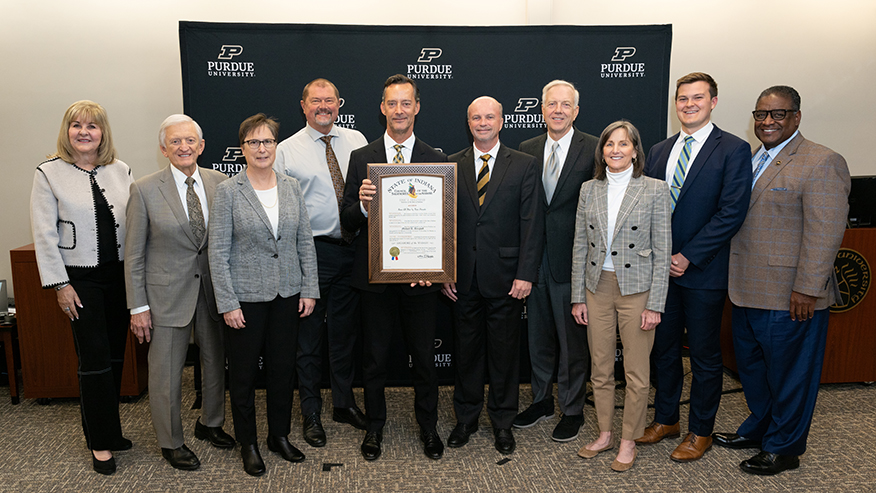 Mike Berghoff holds Sagamore of the Wabash Award, flanked by Purdue trustees