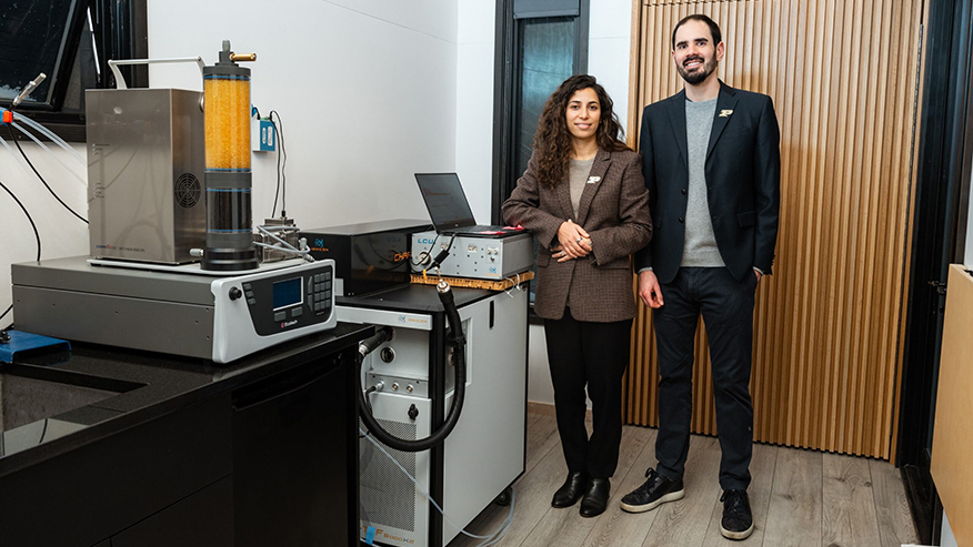 Nusrat Jung and Brandon Boor stand next to measurement equipment in a houselike lab