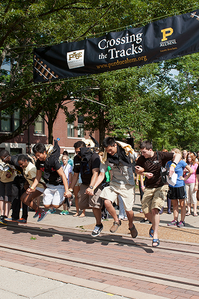 A group of students leaping over the tracks at at Cross the Tracks event