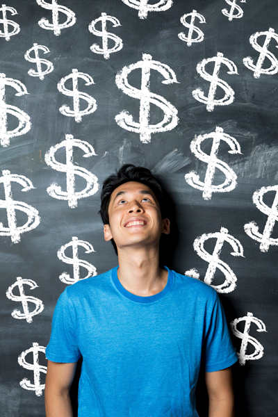 A young man standing next to chalkboard with dollar signs written on it
