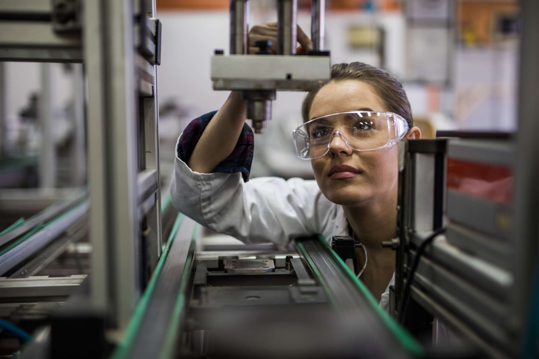Female engineer examining machine part on a production line.