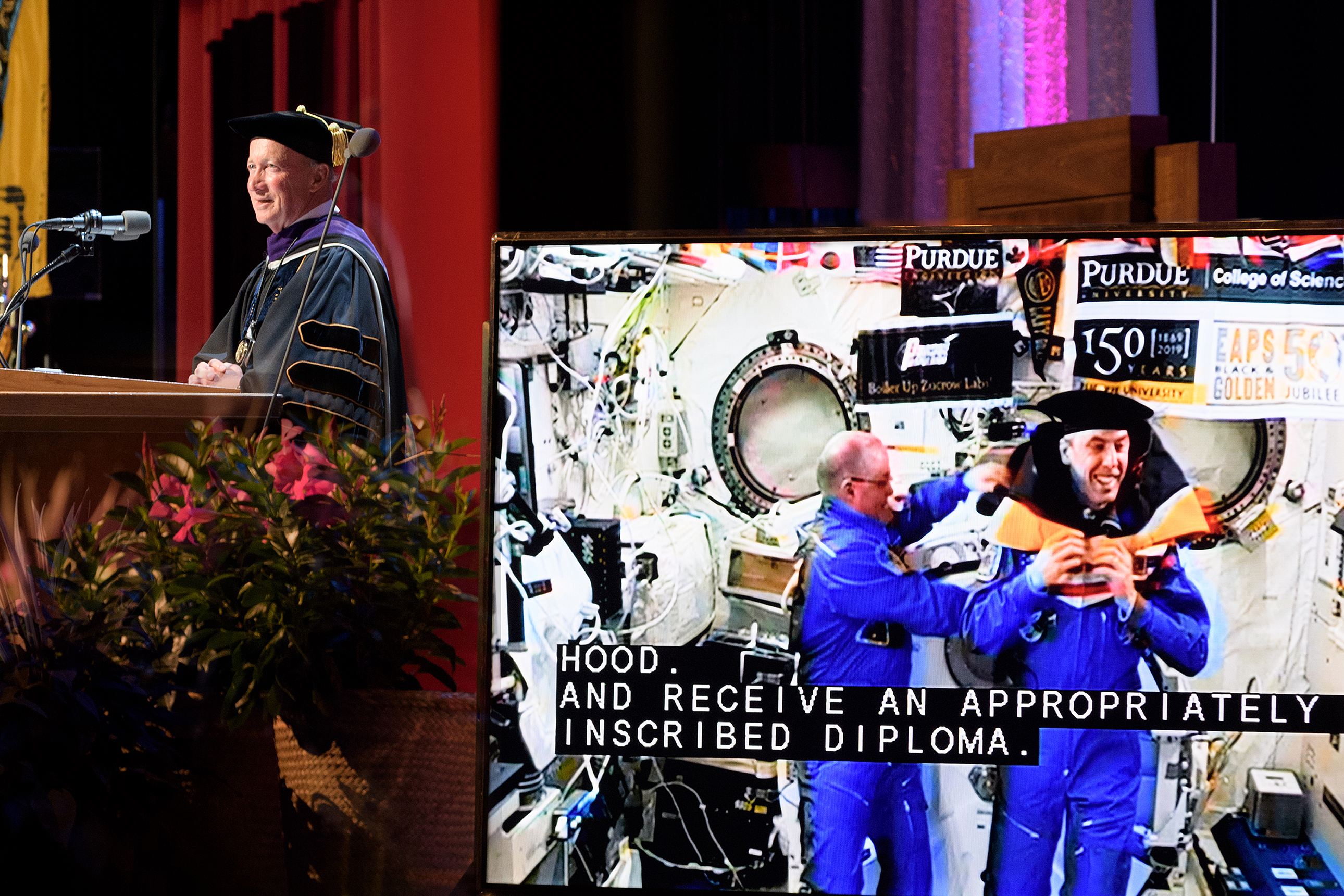NASA astronaut Scott Tingle awards fellow astronaut Drew Feustel the ceremonial hood during a May 2018 Purdue commencement ceremony