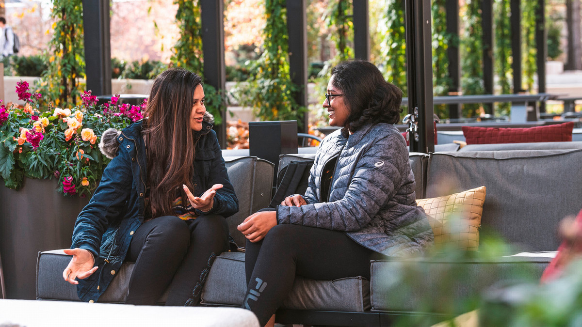 Two students sitting outside and talking. 