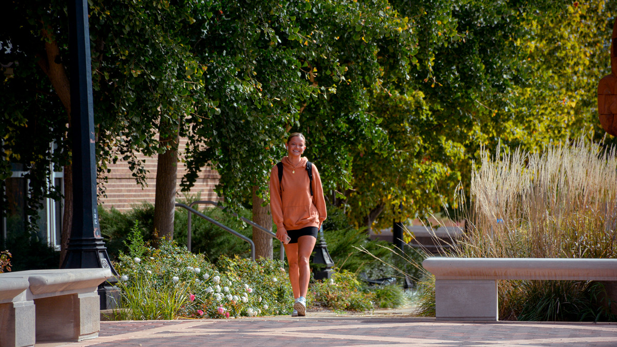 Girl walking on campus in fall. 