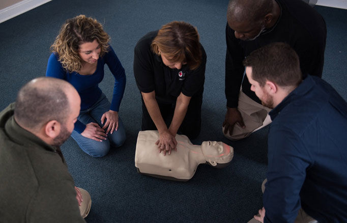 Instructor demonstrating CPR with group watching
