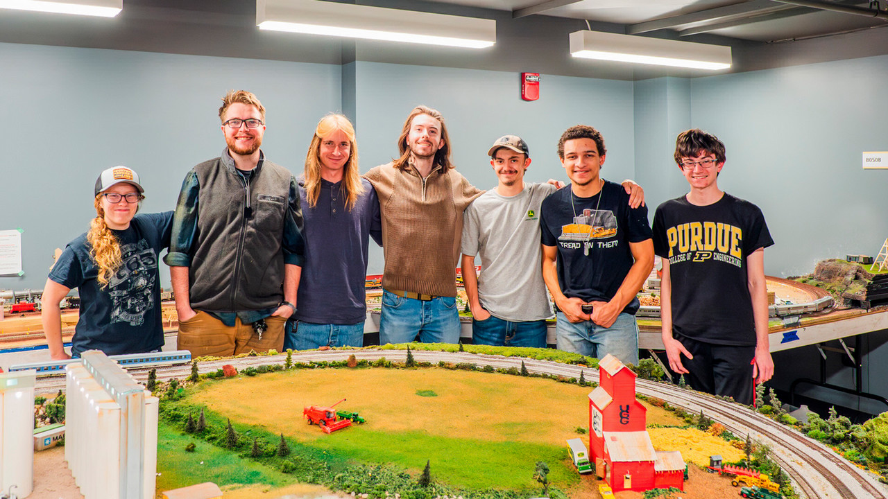 Purdue's Railroad Club pose behind their work of a model train city. 