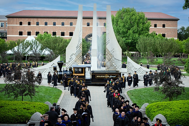 Graduating students celebrate their achievements as they walk past the iconic Class of 1939 Water Sculpture, a symbol of tradition at Purdue University.