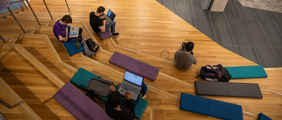 Students studying on the lower-level steps in the Hall of Data Science and AI building.
