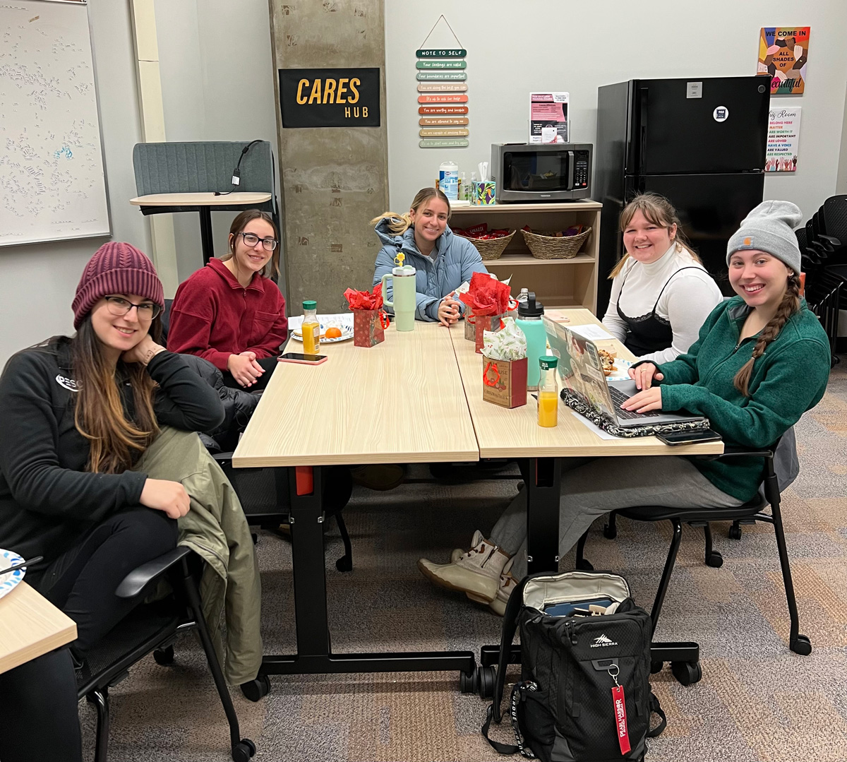 A student staff meeting with a sign in the background that reads "CARES Hub".