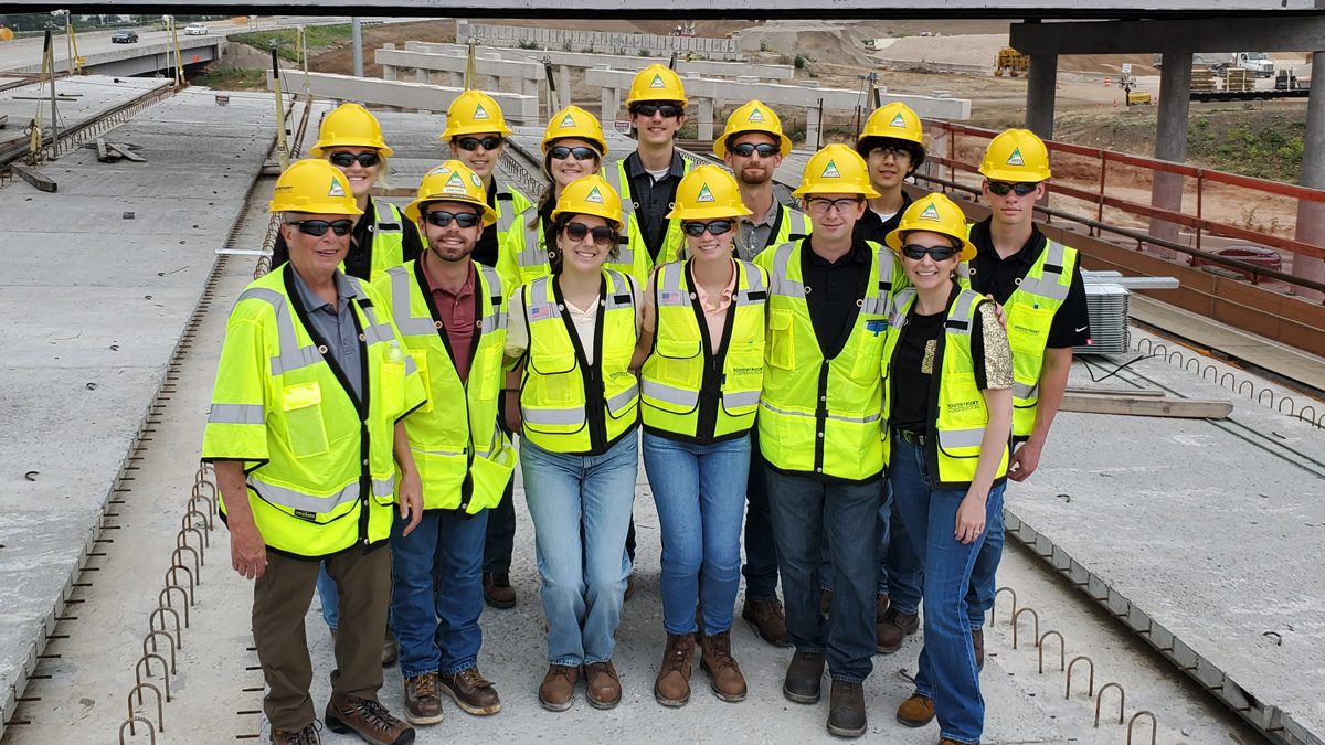 A group of people wearing hard hats and safety vests at a construction site.