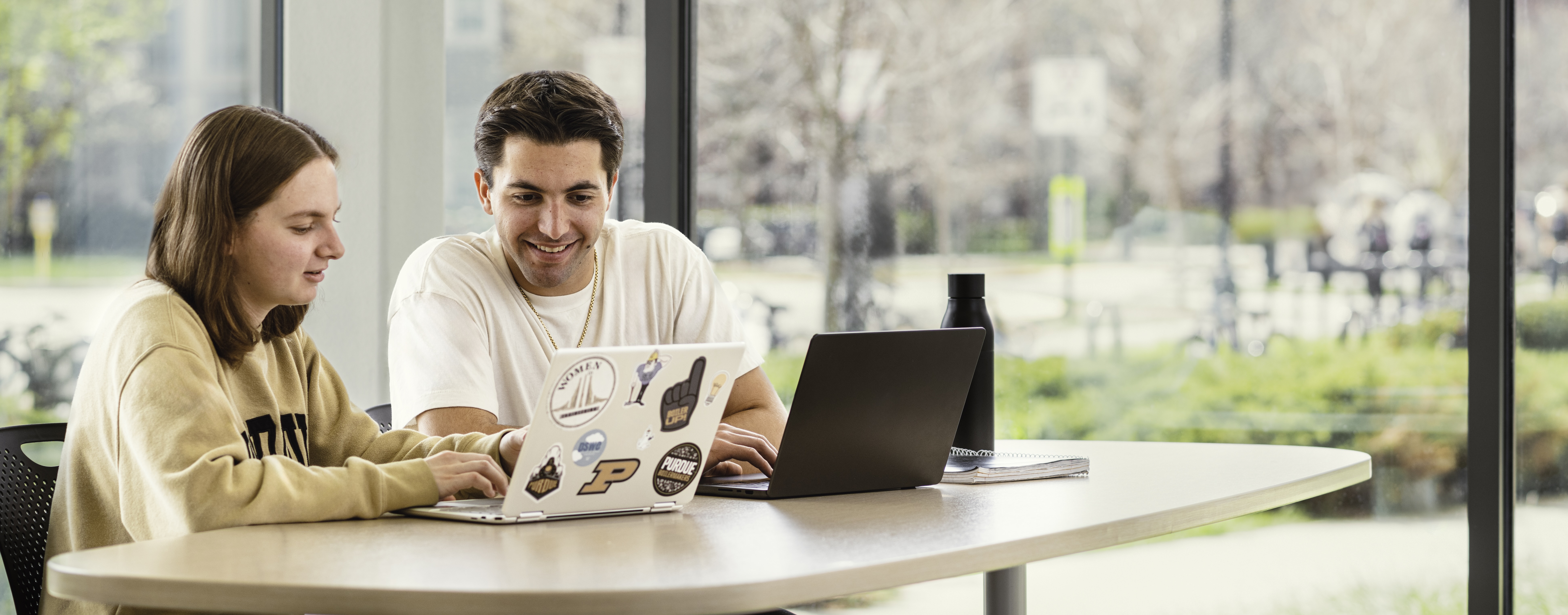 two students working together on one laptop