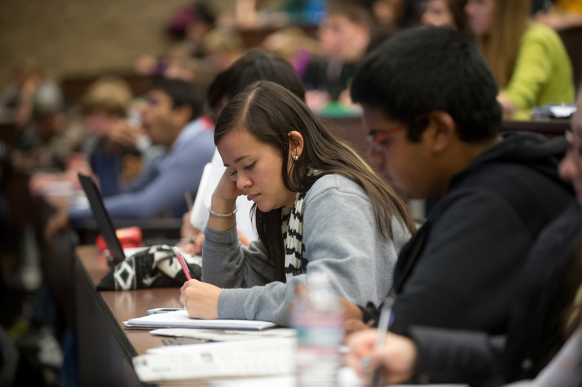 Pictured: students work with their heads down to take notes during class, sitting in a row
