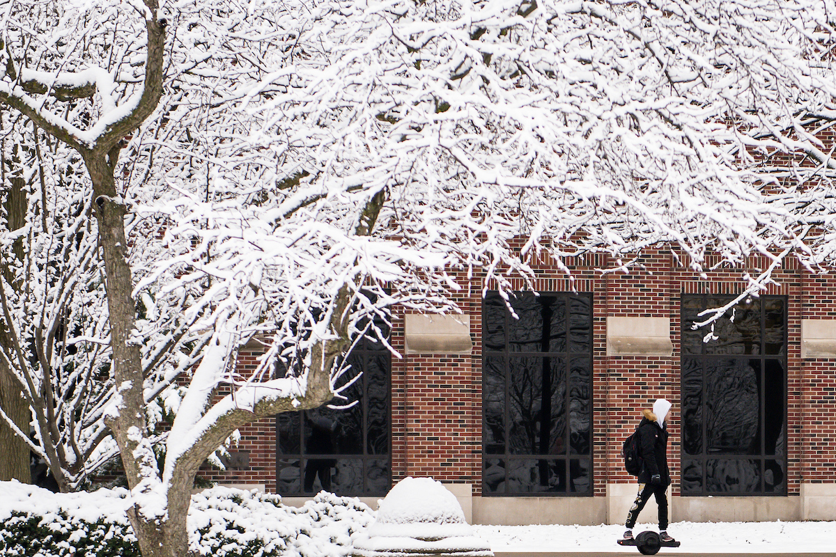 Pictured: student walks alone in the snow on purdue university campus