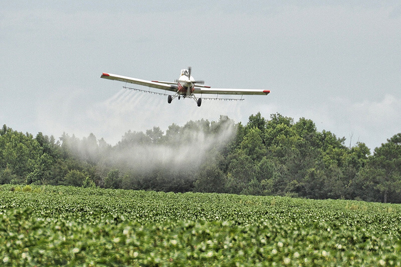 Plane spraying pesticide on field